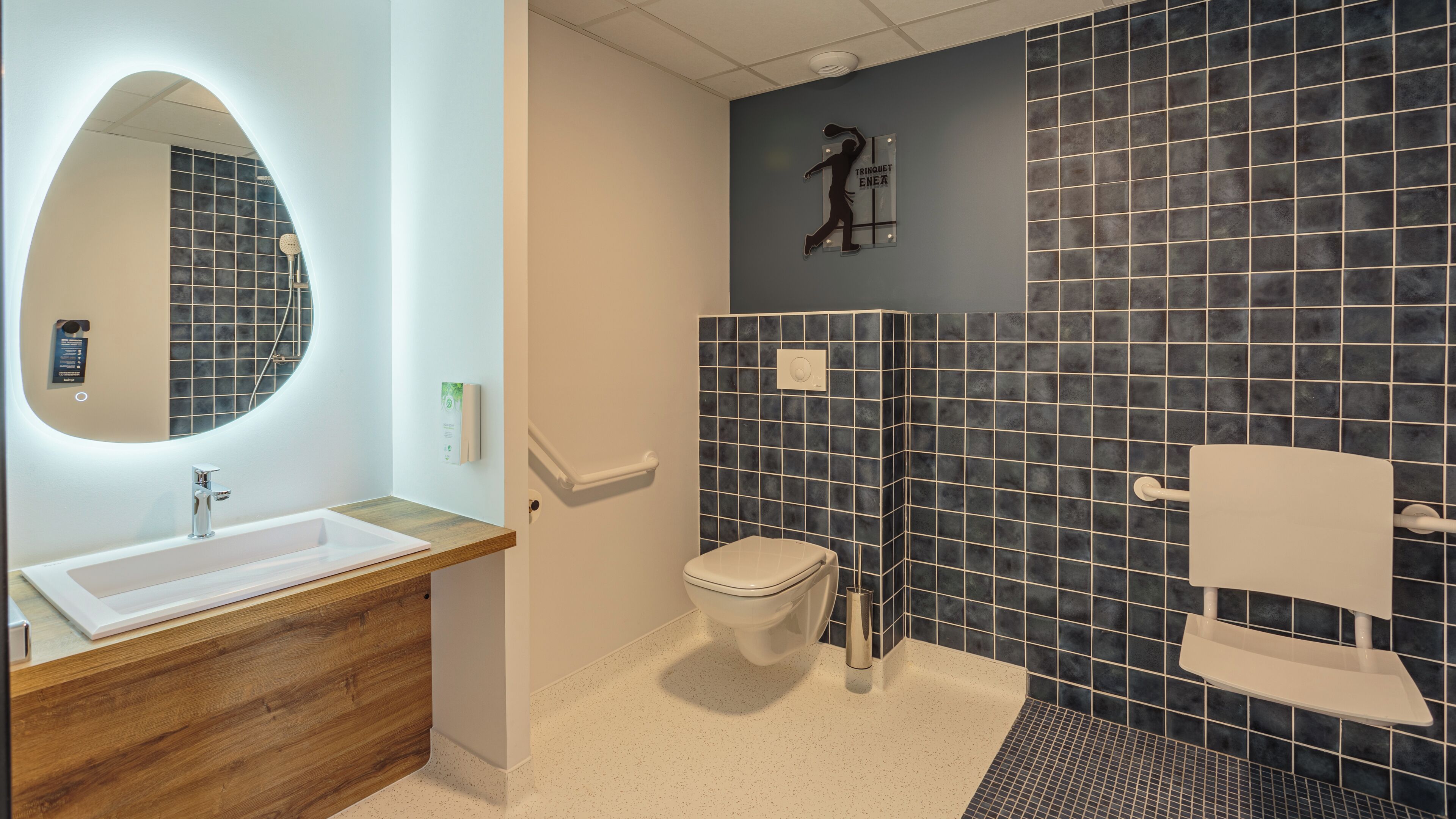 Un baño moderno con un mueble de tocador de madera, un inodoro blanco, zona de ducha y un espejo grande.