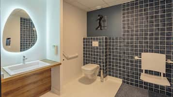 Un baño moderno con un mueble de tocador de madera, un inodoro blanco, zona de ducha y un espejo grande.