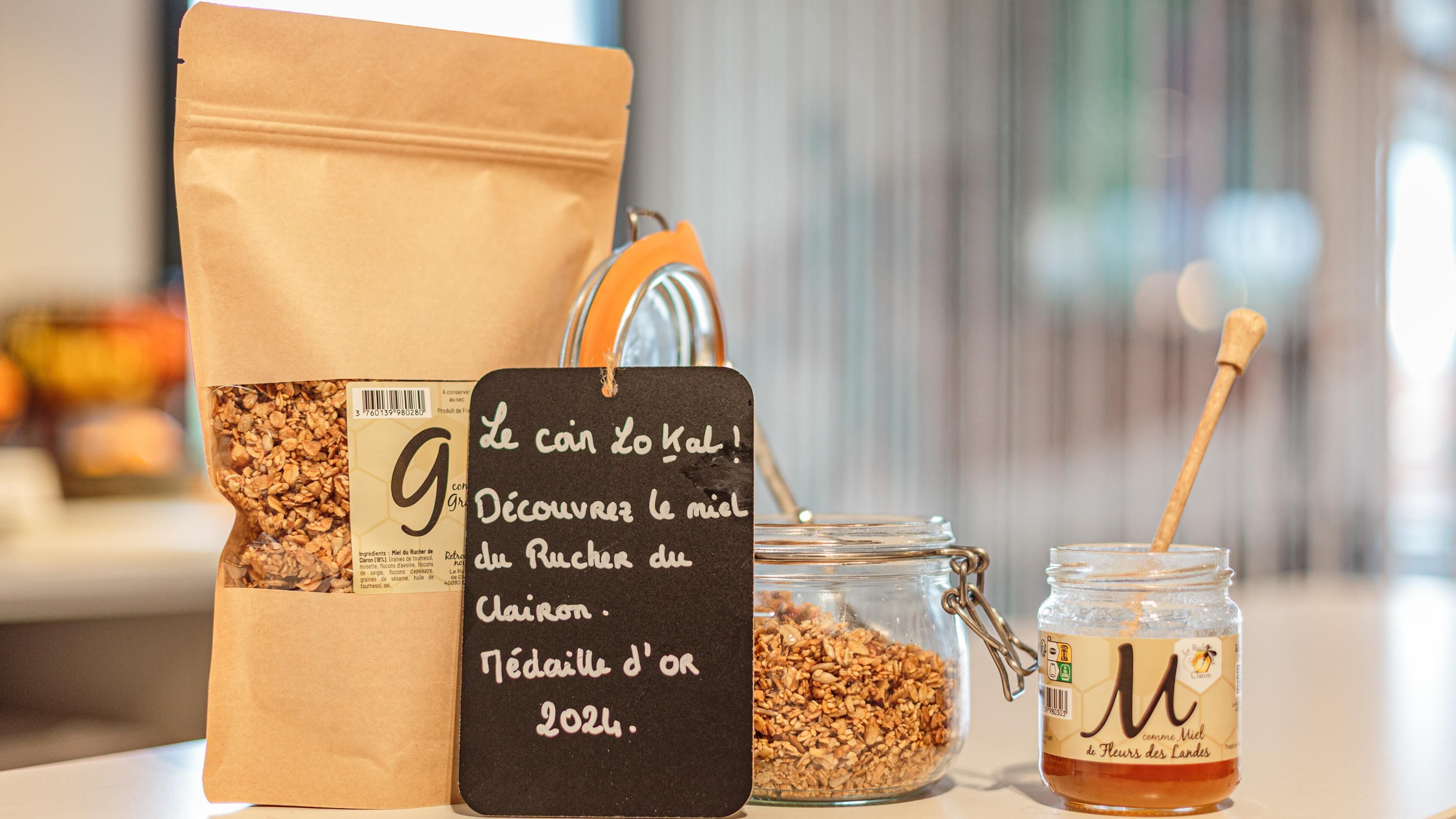 Un paquet de granola, un pot de miel et un cuilleron à miel sur une table.