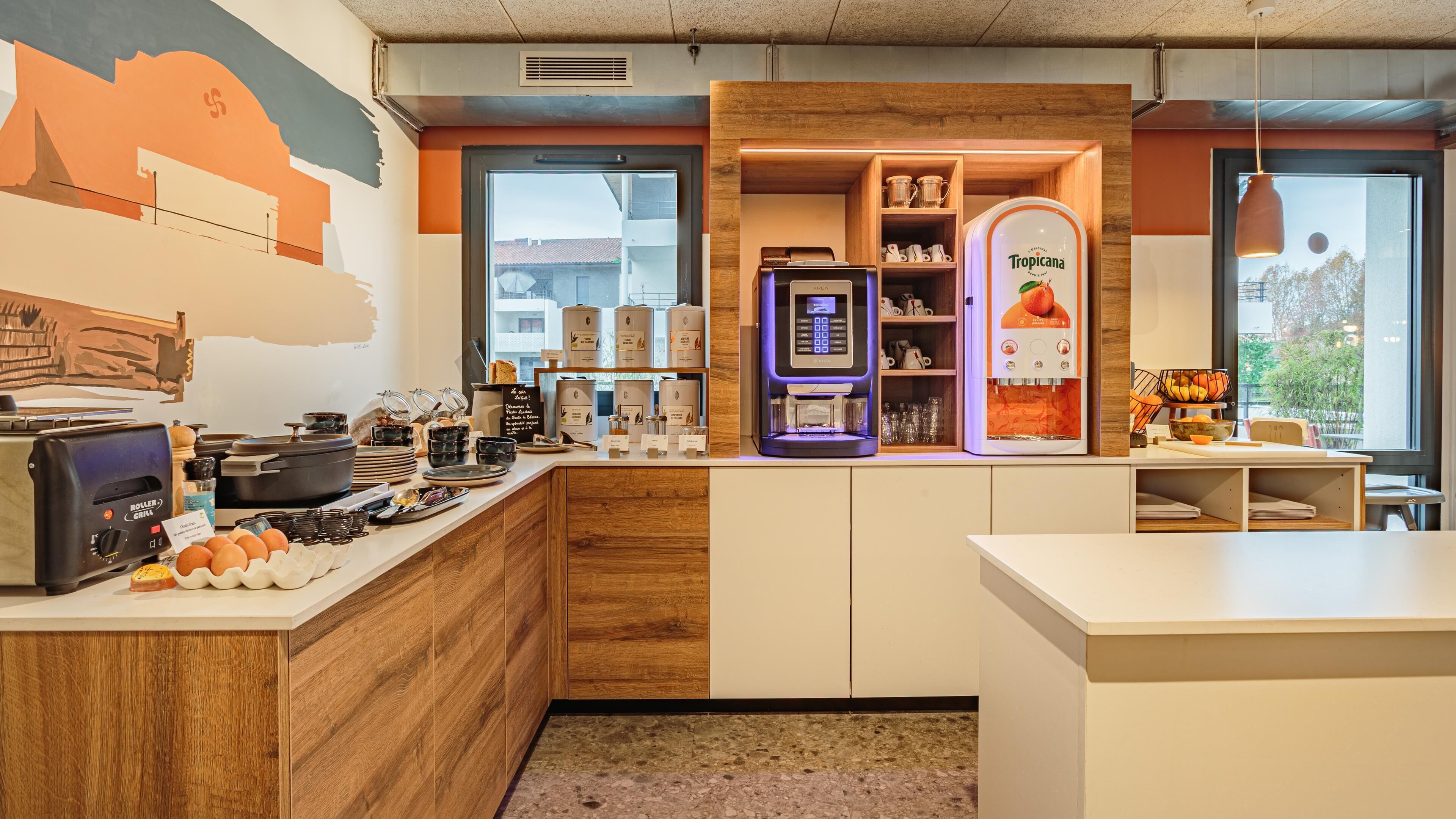 Una cocina moderna con cafetera, dispensador de frutas y exhibición de tazas de café.