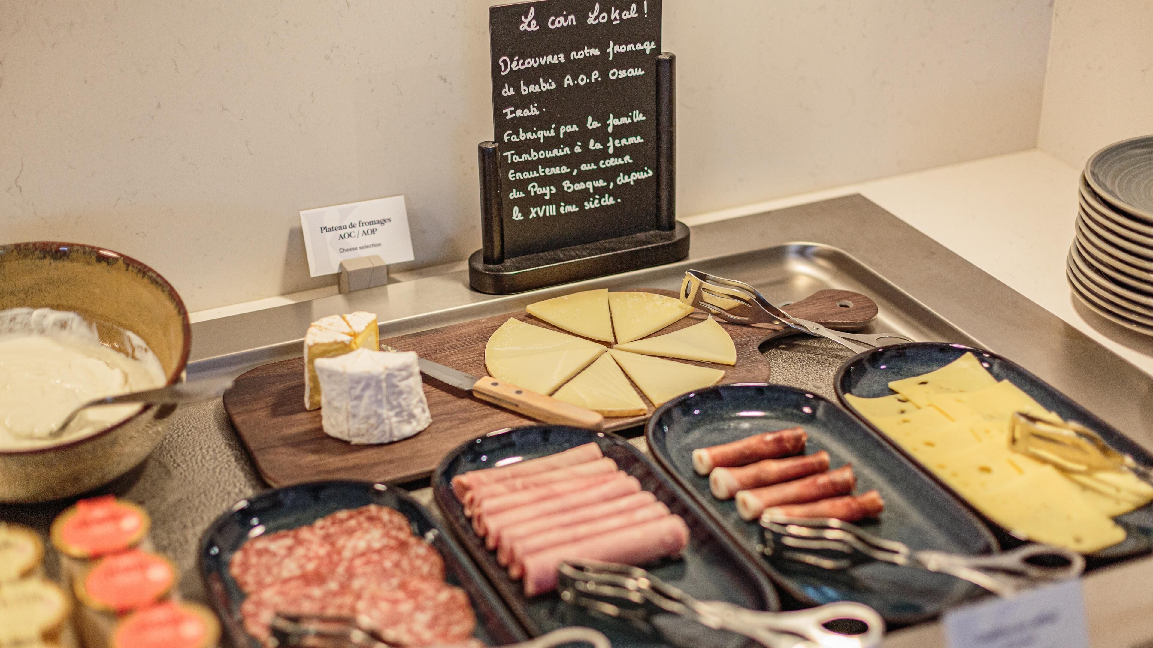 A cheese selection display with various types of cheese and hot dogs.