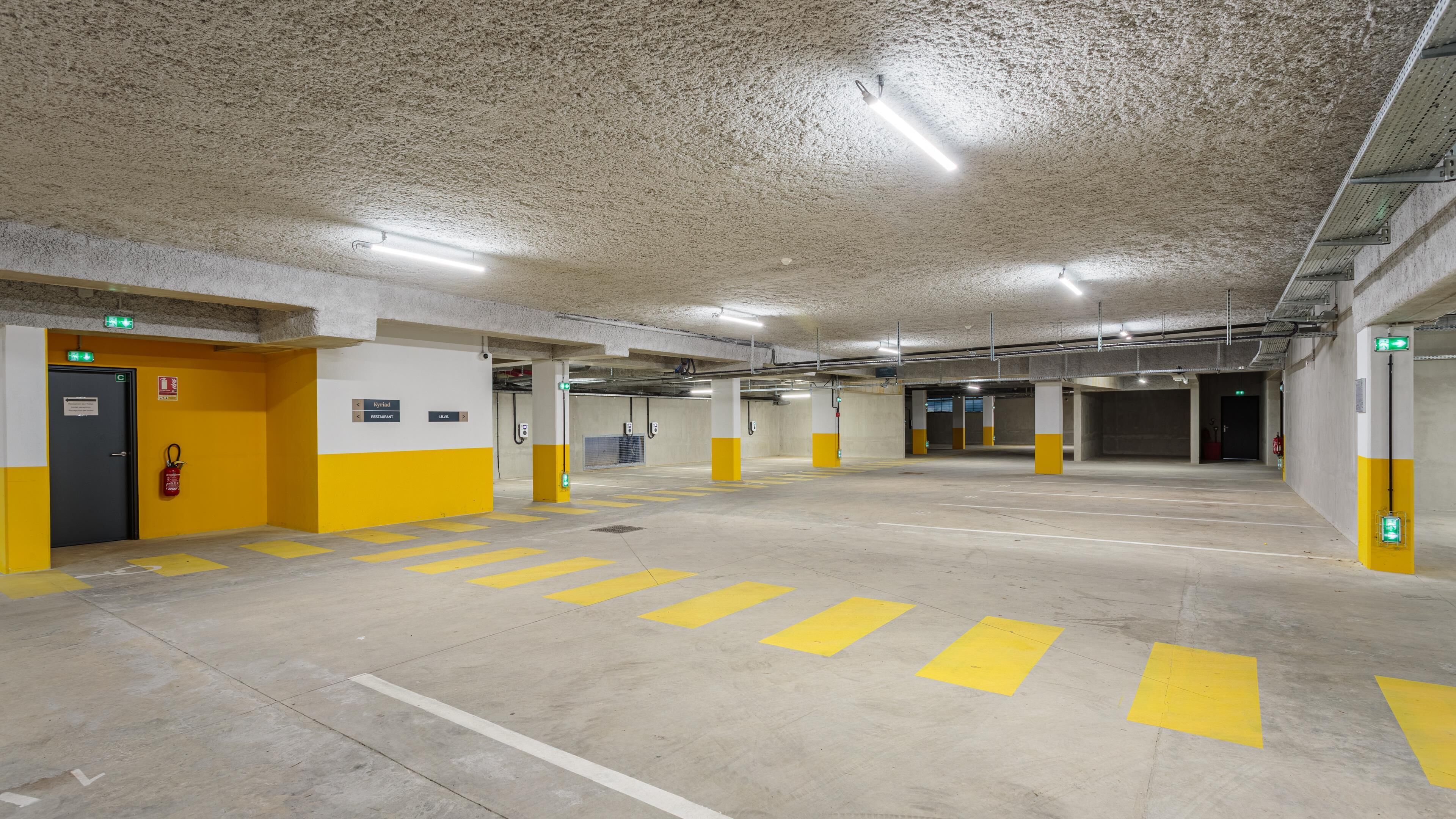 A multi-level underground parking garage with clear signage for exits and amenities.