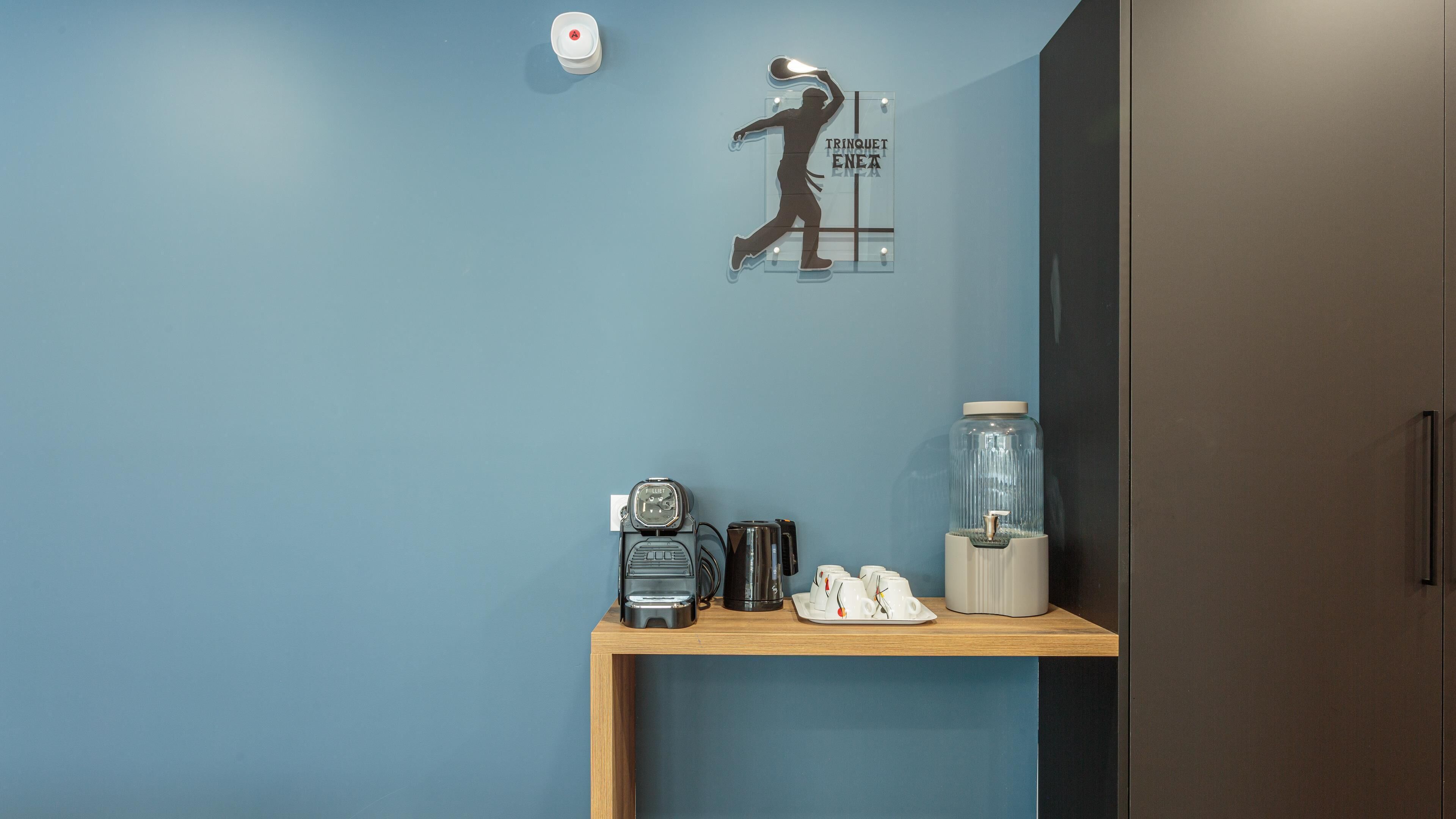 A room with a blue wall, a wooden shelf with a vintage radio, a coffee maker, and a glass jar.