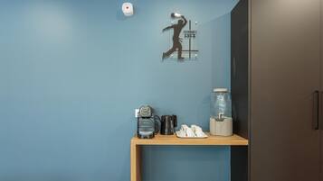 A room with a blue wall, a wooden shelf with a vintage radio, a coffee maker, and a glass jar.