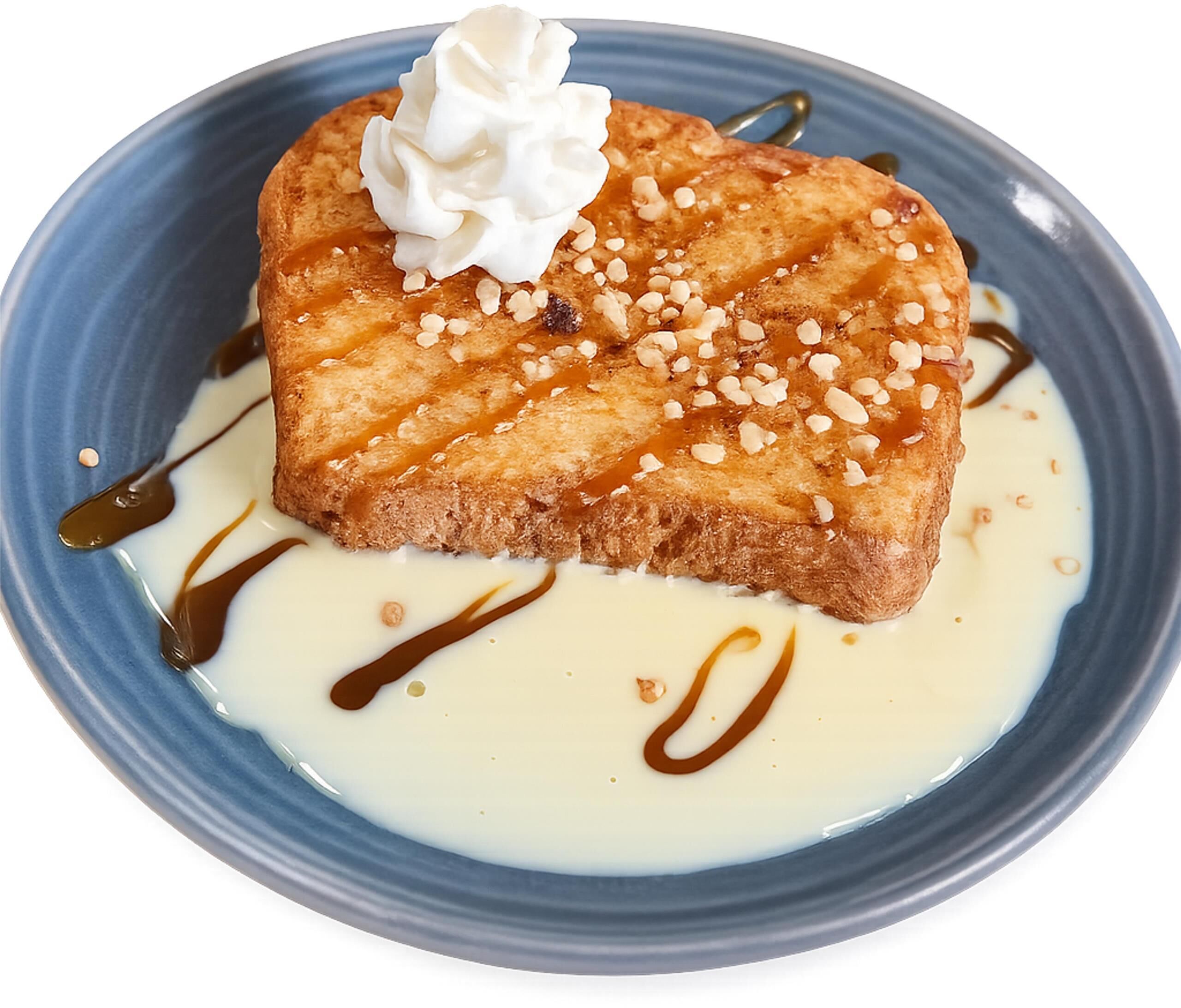 A dessert on a plate with whipped cream, syrup, and nuts.