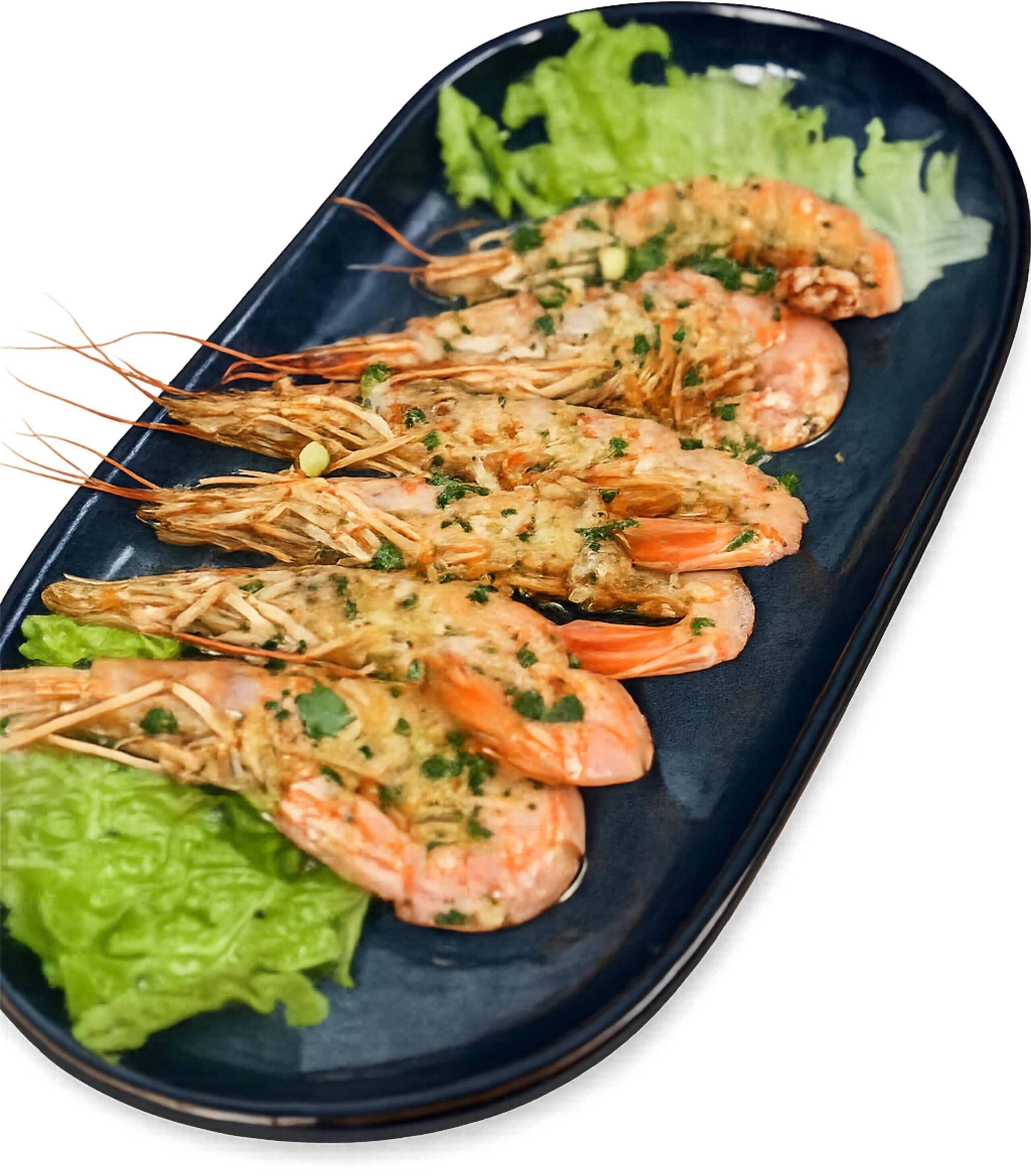 Un plato de camarones cocidos, adornado con hierbas, servido sobre un plato oscuro con lechuga verde.
