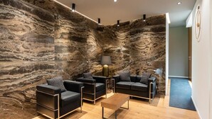 A modern living room with a stone wall, black leather sofas, a wooden coffee table, and a lamp. - Cozy room with whirlpool bath and kitchenette in the center of Palermo (Palermo)