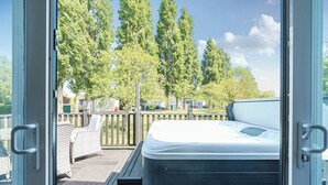 A hot tub with a wooden deck and a view of a residential area with trees and houses. - Aquadrome Abode - Billing Aquadrome (Northampton)