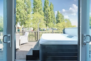 A hot tub on a deck with a view of trees and a fence.