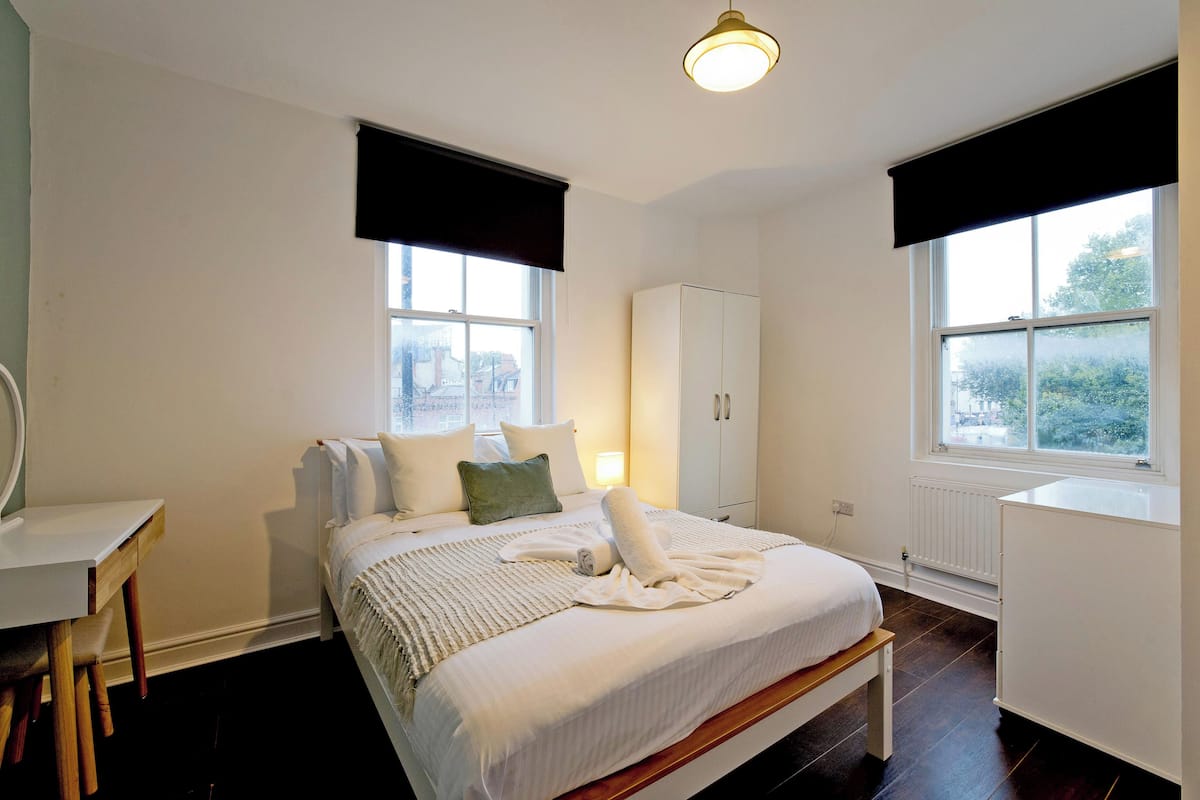 Une chambre à coucher comprenant un lit, une table de chevet, une armoire et une fenêtre donnant sur l’extérieur.
