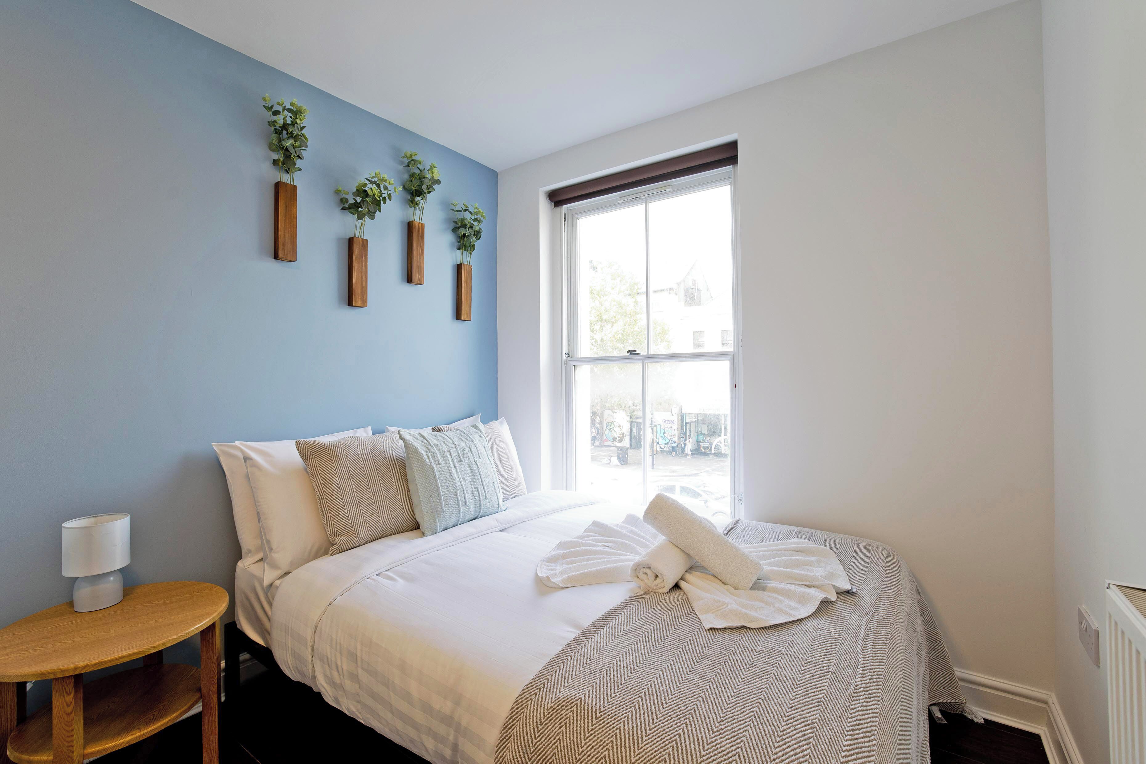 A bedroom with a bed, bedside table, and a window with a view.