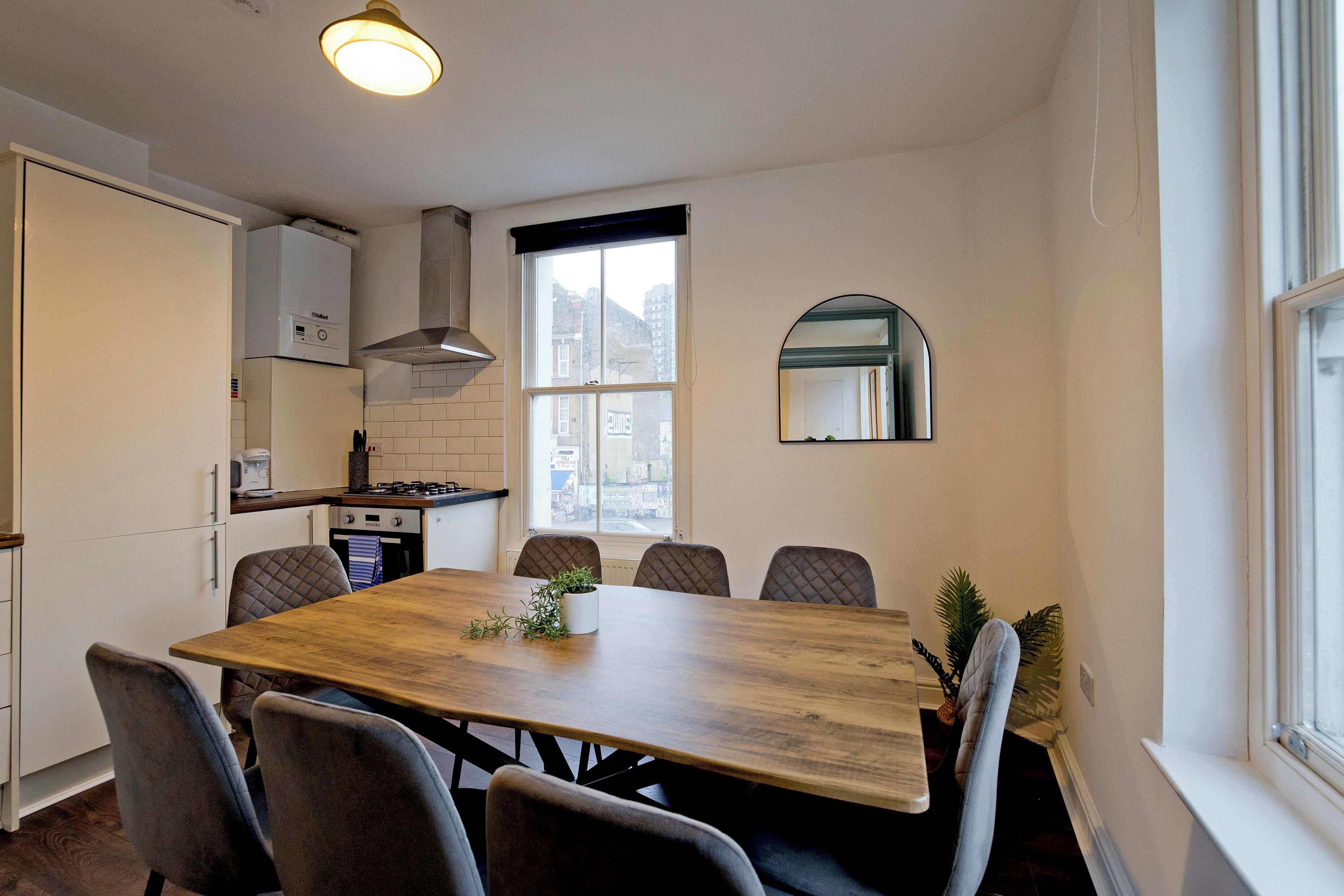 A compact kitchen with a dining area, a built-in oven, and a window with a view of buildings.