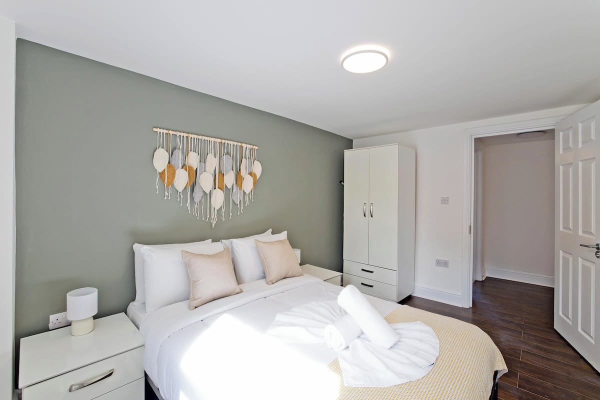 Une chambre bien rangée, avec un lit, une table de chevet, une armoire et un élément décoratif mural.