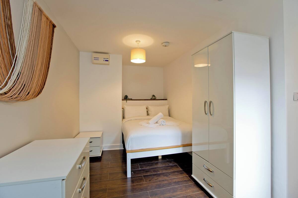 Une chambre à coucher comprenant un lit, une armoire, une table de chevet et un luminaire suspendu.