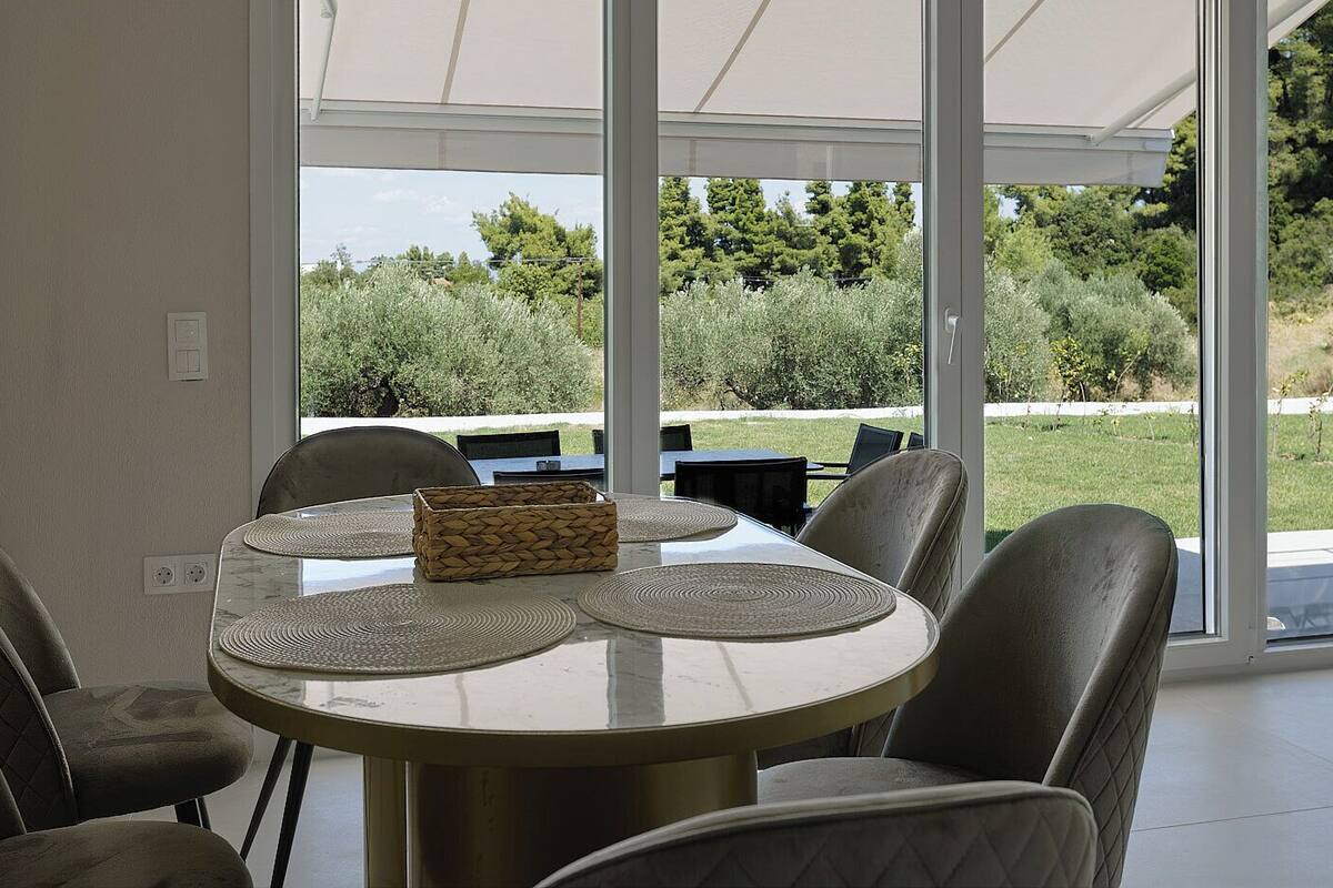 Zona pranzo con tavolo rotondo, sedie e vista sull'esterno.