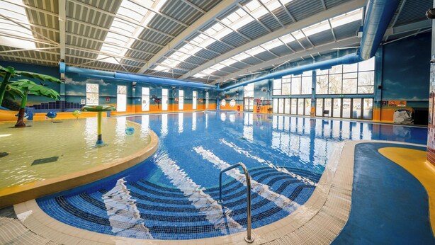 An indoor swimming pool with a curved design, large windows, and a high ceiling. - Lakeside Lullaby - Billing Aquadrome (Northampton)