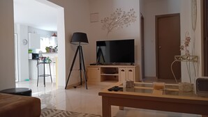 En moderne stue med et fladskærms-tv, en gulvlampe og et sofabord.