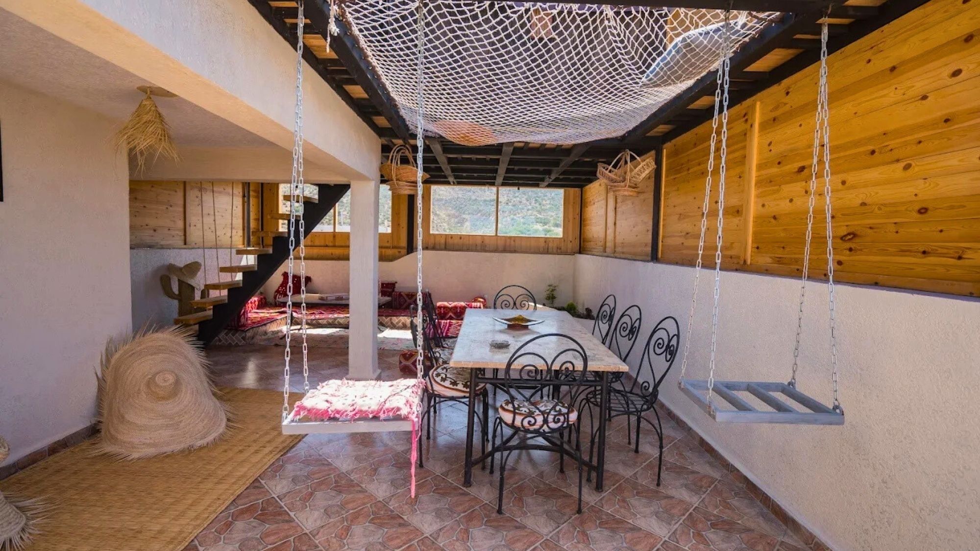 Un interno rustico in legno con un tavolo da pranzo, sedie e un'altalena.