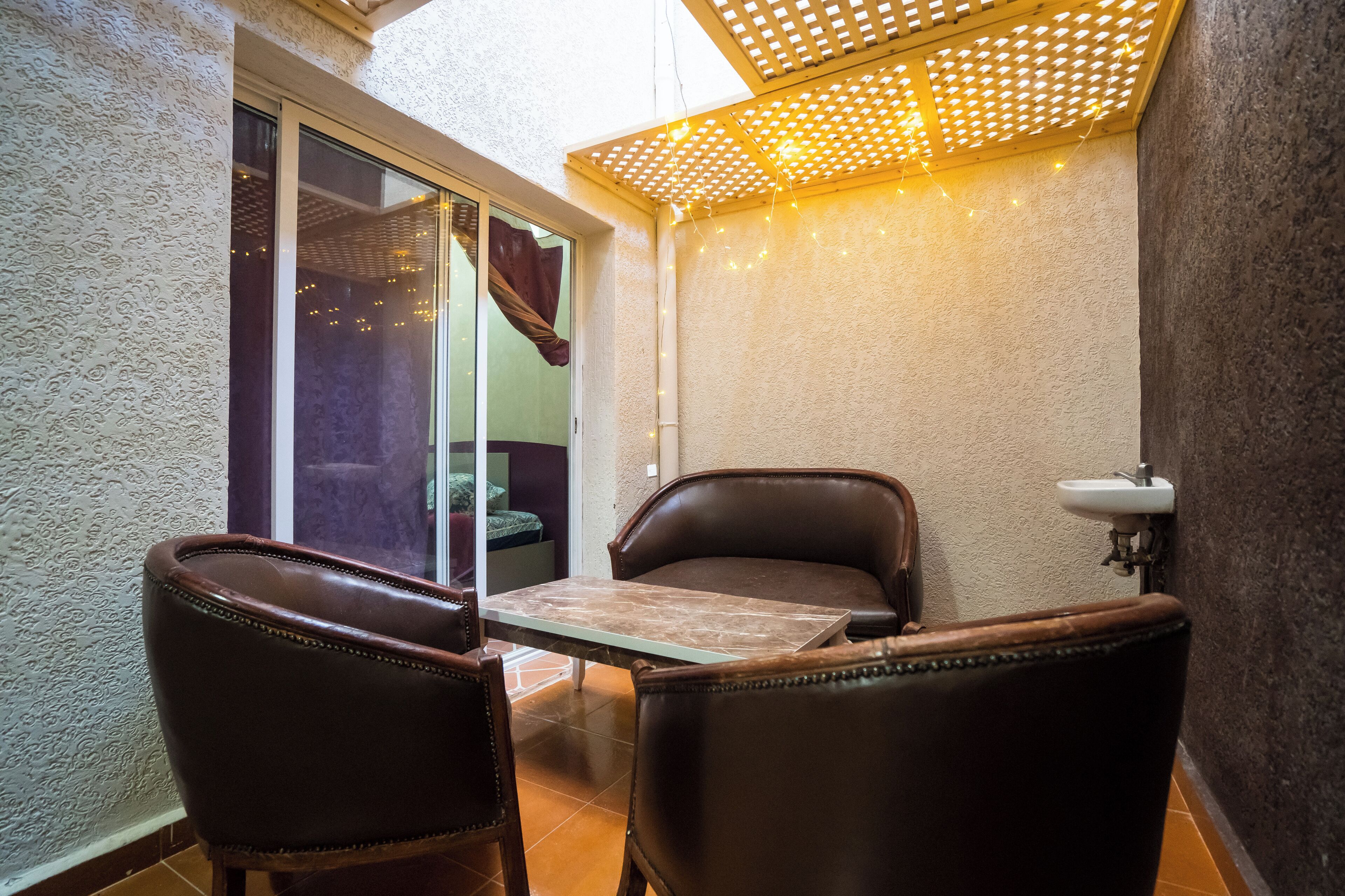 A small patio with a table and two chairs, a sliding glass door, and a ceiling with a wooden lattice.