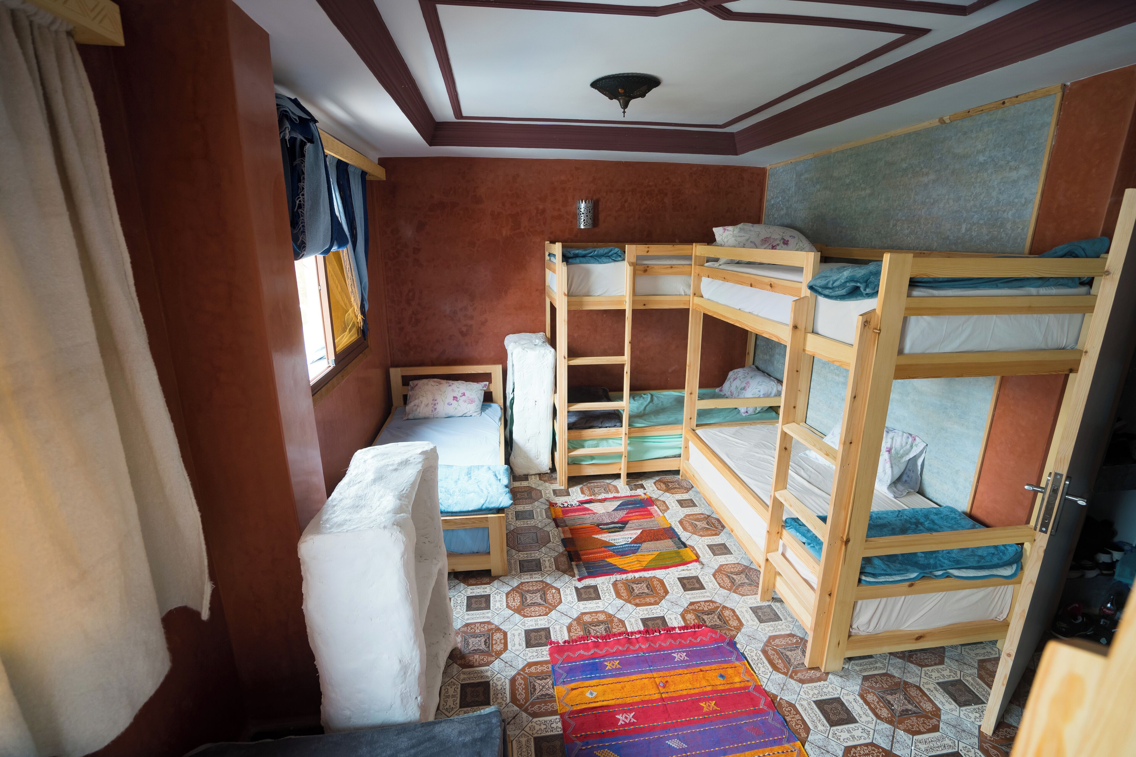 A compact room with bunk beds, a window with curtains, and a patterned floor.