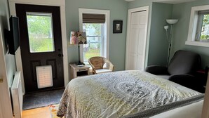 A bedroom with a bed, a chair, a desk, and a radiator.