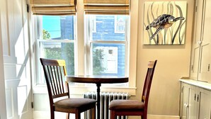 A kitchen with a dining table, chairs, a radiator, and a window with blinds.