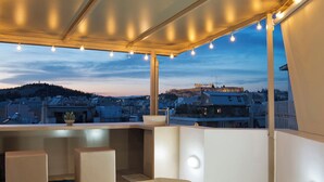 A rooftop terrace with a hot tub, seating area, and string lights.