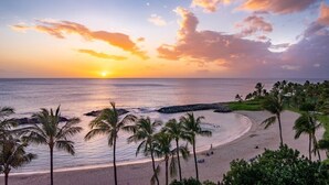 A beach with palm trees and a sunset.