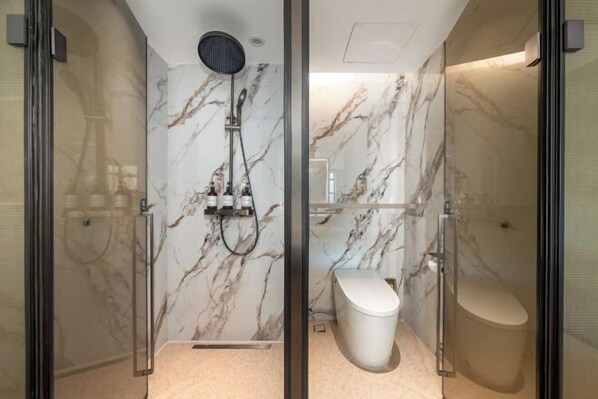 A modern bathroom with a glass-enclosed shower, marble walls, a toilet, and a sink. - Langyi Hotel (Guangzhou Tower Pazhou Exhibition Center Branch) (Guangzhou)