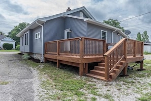 A single-story house with a wooden deck and a staircase leading to the front door.