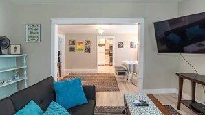 Una sala de estar con sofá, televisor y comedor con mesa y sillas.