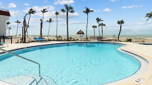 Una piscina con palmeras y una playa al fondo.