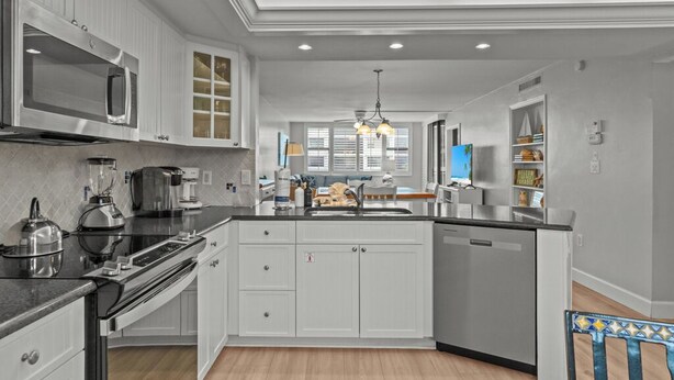 A modern kitchen with white cabinetry, stainless steel appliances, and a central island.
