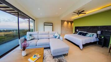 Un dormitorio moderno con una cama grande, un sofá y vistas al campo.