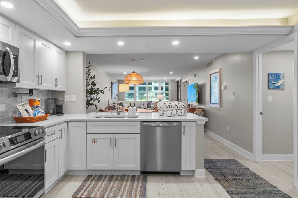 Une cuisine moderne avec des meubles blancs, un îlot central, un lave-vaisselle et un four à micro-ondes.