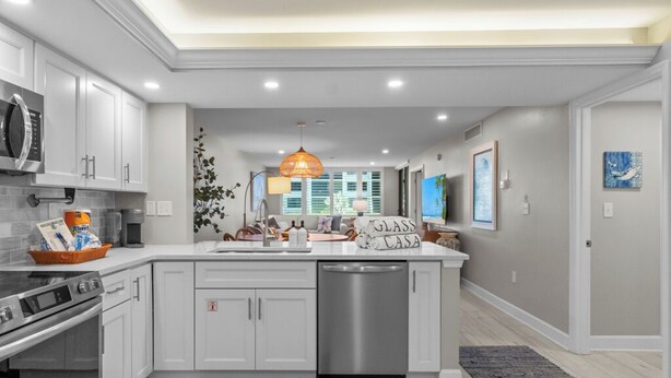 A modern kitchen with white cabinetry, a central island, a dishwasher, and a microwave.