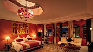 Une chambre d’hôtel avec un grand lit, un canapé, une table basse et un lustre.