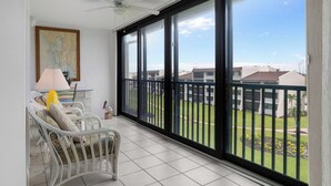 Ein Balkon mit einem weißen Stuhl, einer Lampe und einem Deckenventilator.