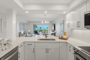 A modern kitchen with white cabinetry, a stainless steel sink, and a built-in oven.