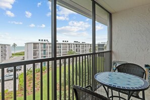 A balcony with a view of a beach and other buildings.