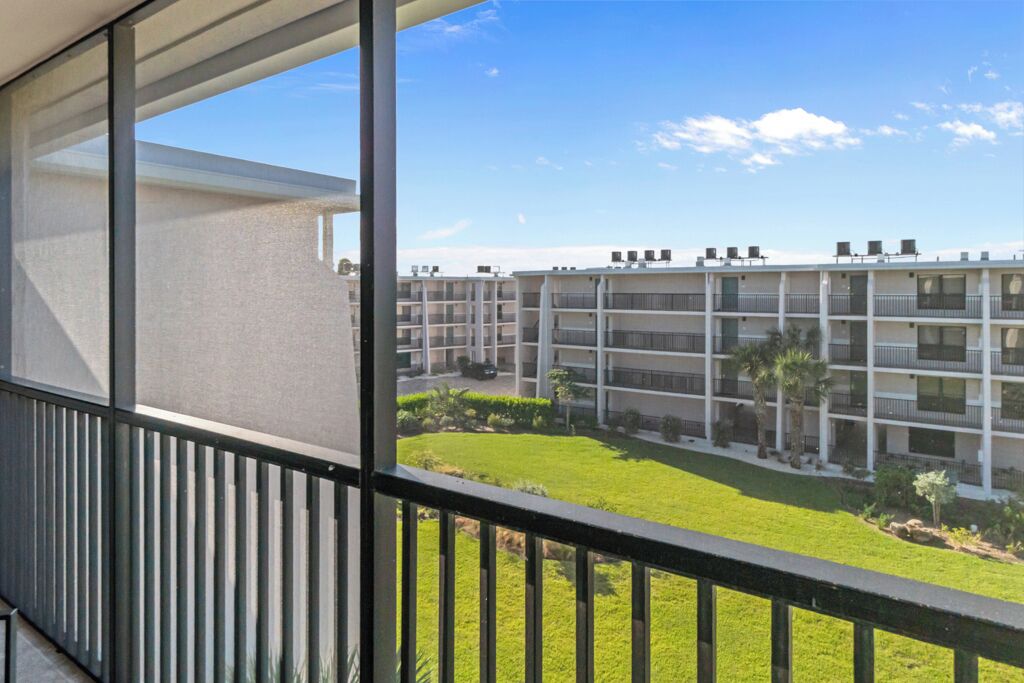 Un immeuble moderne à plusieurs étages, doté de balcons, d’une pelouse bien entretenue et surplombant un ciel dégagé.