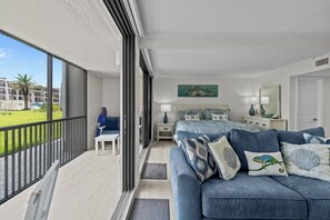 A bedroom with a large bed, a balcony, and a view of a green landscape.