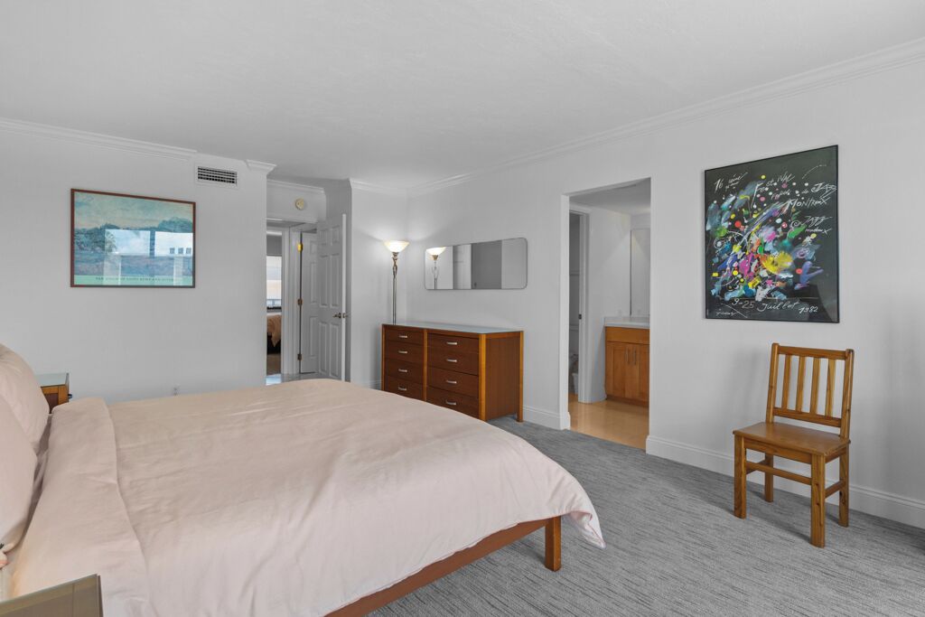 A bedroom with a bed, a dresser, a chair, and two paintings on the walls.