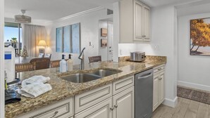 A modern kitchen with granite countertops, stainless steel appliances, and white cabinetry.