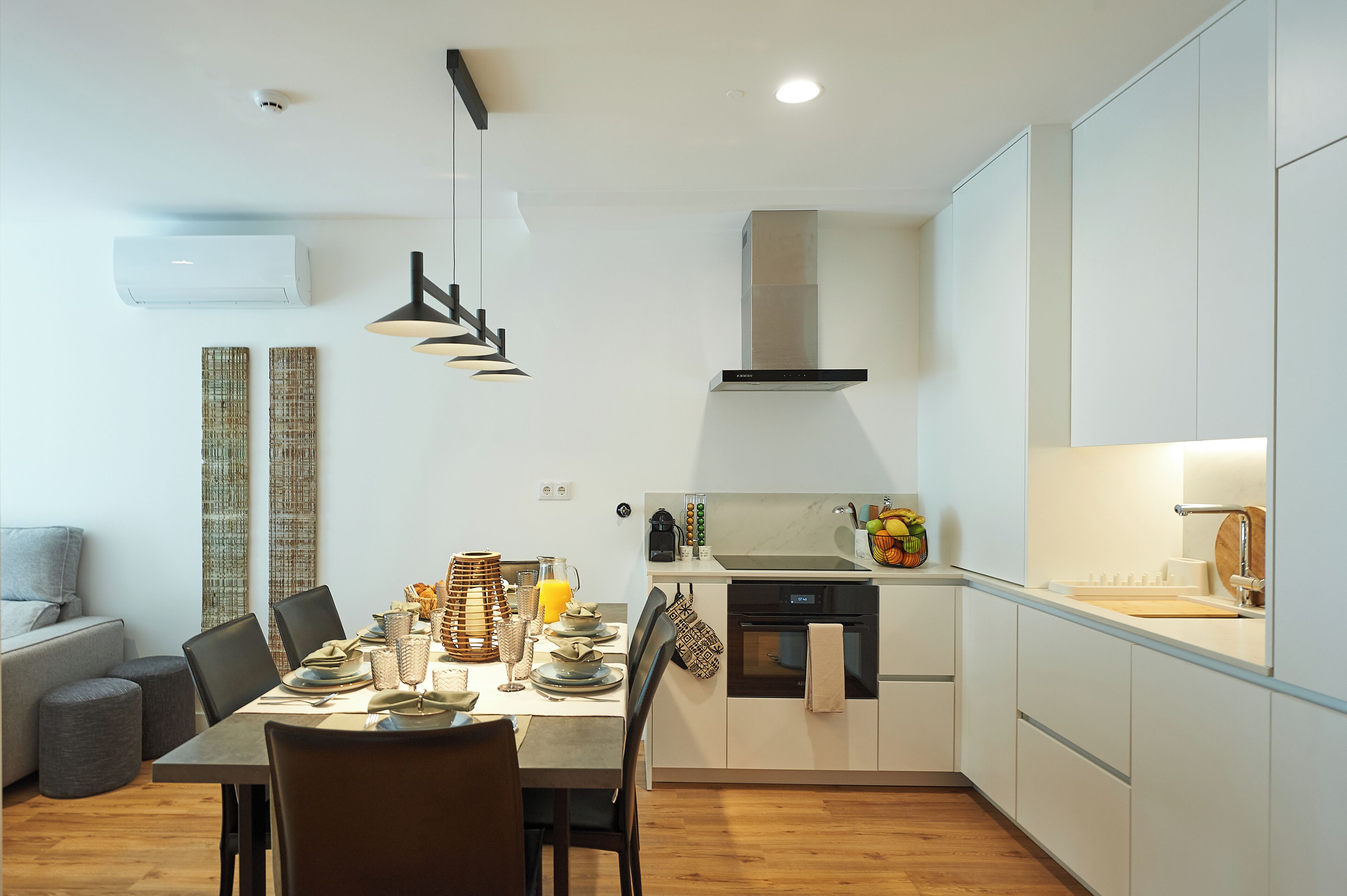 Een moderne keuken met witte kasten, een ingebouwde oven en een eethoek met een tafel voor vier personen.