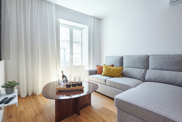 Una sala de estar moderna con un sofá gris, una mesa de centro de madera y una planta en maceta.