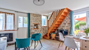 Une cuisine moderne avec un mur en pierre, un escalier en bois et des chaises de couleur turquoise.