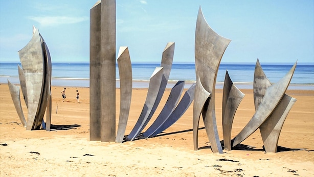Une plage parsemée de sculptures métalliques, offrant une vue dégagée sur l’océan.