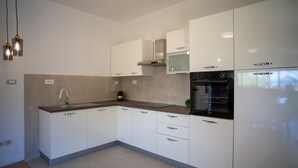 A modern kitchen with white cabinets, a stainless steel oven, and a built-in microwave.