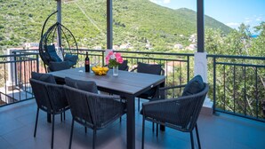 A covered outdoor seating area with a table, chairs, and a hanging chair.